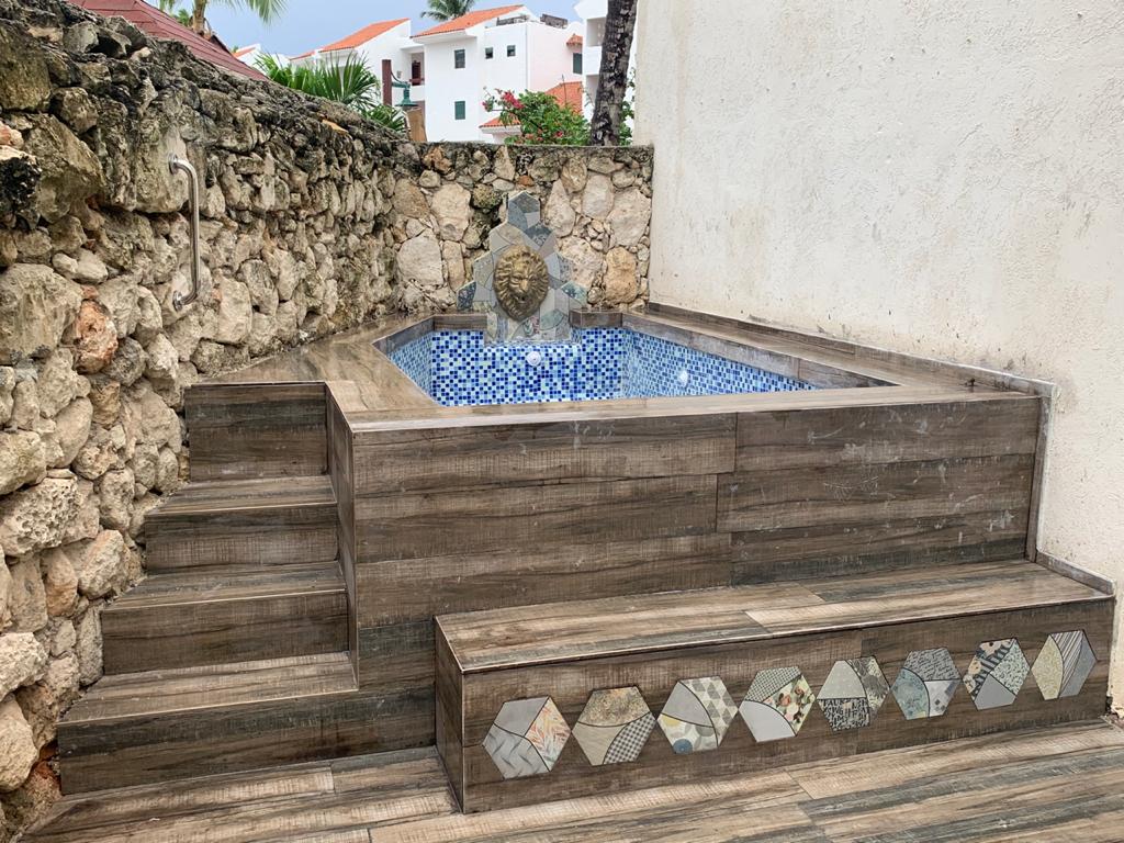 Private jacuzzi plunge pool with blue mosaic tiles and coral stone wall — villa for sale in Punta Cana