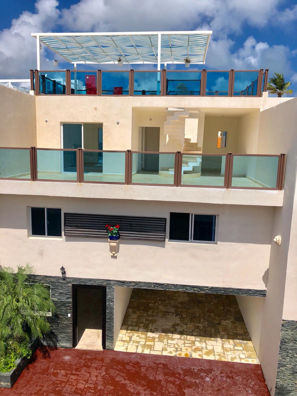 Three-level villa front facade with rooftop terrace and covered parking — buy property in Punta Cana