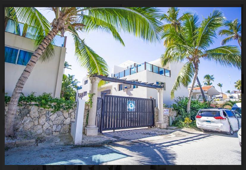 Secure gated community entrance with palm trees — luxury villa in Punta Cana, Dominican Republic